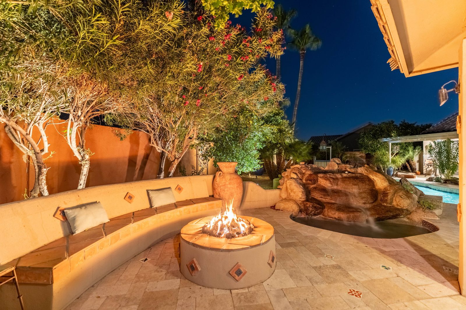Volcanic rock fire pit and waterfall lit at night